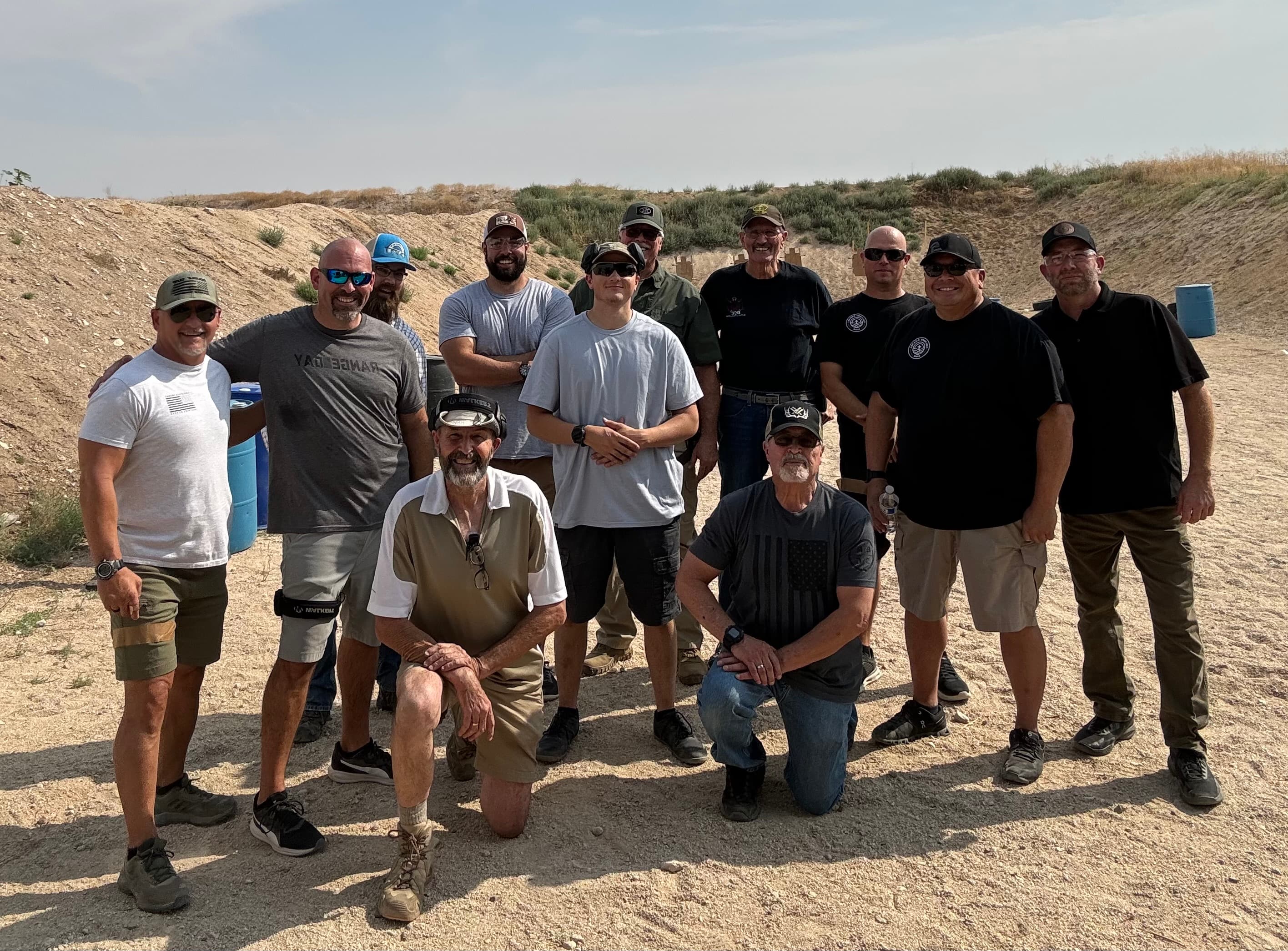 group of guys smiling on the range after finishing defensive pistol class